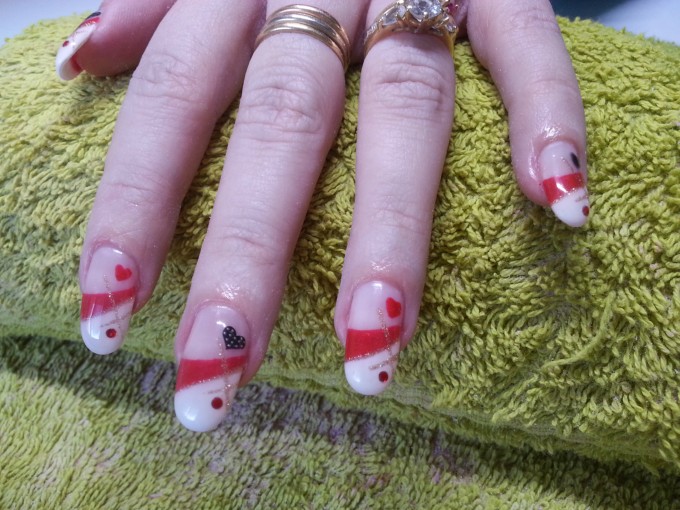 Ongles en gel avec déco french blanche, rouge trait or pailleté, strass, stickers coeurs forme amande